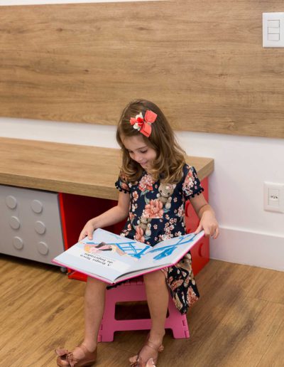 Criança lendo um livro na recepção do consultório de Dra. Ludmilla Athayde